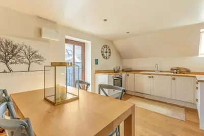 a kitchen with a table and chairs and a clock on the wall at Hilltop View with Hot Tub in Brecon