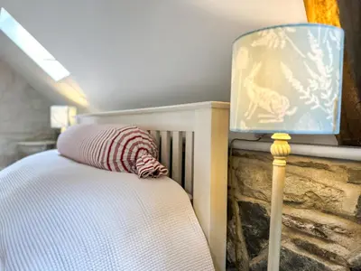 a bed with a striped pillow and a lamp at Meadow Barn in Shelve