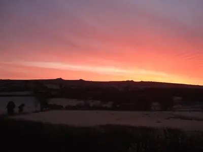 a sunset with a person standing in a field at Meadow Barn in Shelve