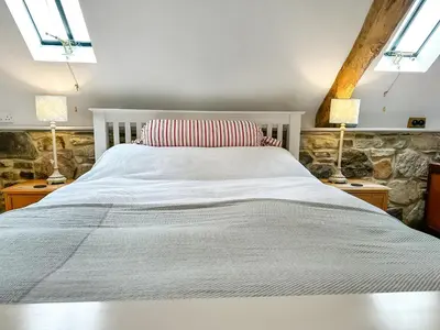 a bedroom with a white bed with two lamps at Meadow Barn in Shelve