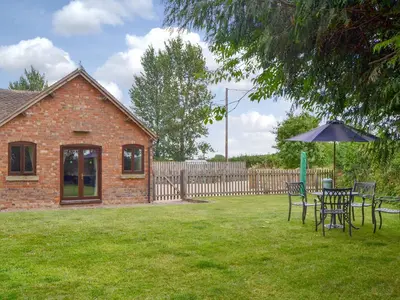 a table and chairs with an umbrella in a yard at Skimblescott Barn in Monkhopton