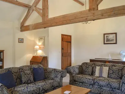 a living room with two couches and a table at Skimblescott Barn in Monkhopton