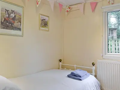a bedroom with a bed and a window with pink flags at The Summer House in Easthope
