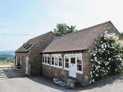a small brick building with a bush with white flowers at Bequia - Reet in Frodesley