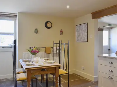 a dining room with a table and a clock on the wall at Bequia - Reet in Frodesley