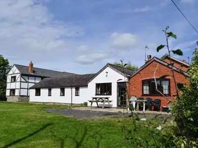 a white cottage with a brick building at Grove Sprightly Barn in Craven Arms