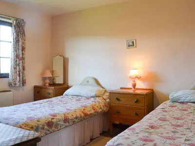 a bedroom with two beds and a dresser and a mirror at Dinhope Big Barn in Craven Arms