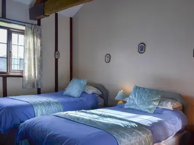 a bedroom with two beds with blue sheets and a window at Dinhope Big Barn in Craven Arms