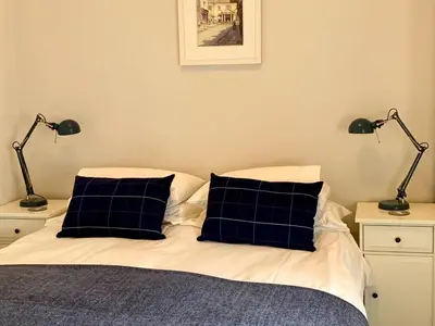 a bed with black and white pillows and two lamps at Cow Shed in Farden