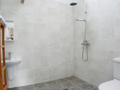 a bathroom with a shower with a toilet and a sink at Cow Shed in Farden