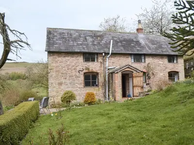 an old brick house on a grassy hill at Titchbourne Cottage in Clee Saint Margaret