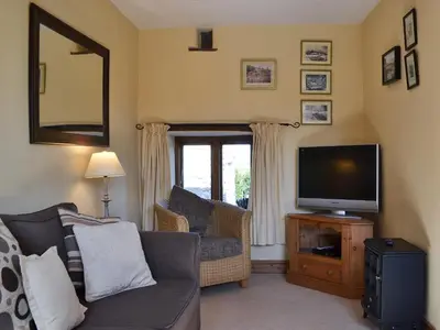 a living room with a couch and a television at Oak Barn Cottage in Trefonen