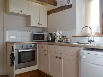 a kitchen with white cabinets and a microwave at Oak Barn Cottage in Trefonen