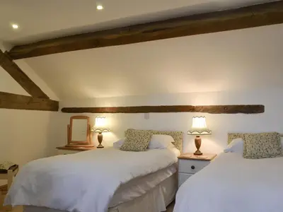 two beds in a room with two lamps on tables at Oak Barn Cottage in Trefonen