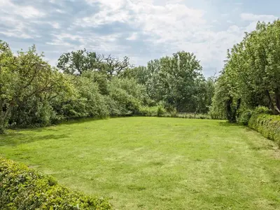 a large field of grass with trees in the background at Cronkhill Farmhouse in Wroxeter