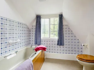 a bathroom with a toilet and a tub and a window at Walnut Tree Cottage in Bucknell