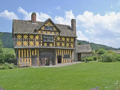 an old house with a green field in front of it at Walnut Tree Cottage in Bucknell