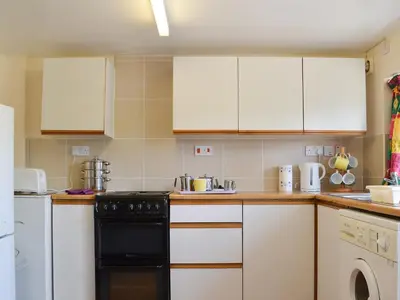 a kitchen with white cabinets and a black dishwasher at The Cider Mill Cottage in Orleton