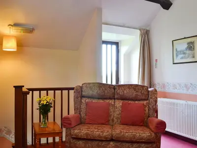 a living room with a couch and a vase of flowers at The Cider Mill Cottage in Orleton