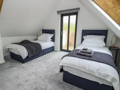 a bedroom with two beds and a window at The Larches in Bishops Castle
