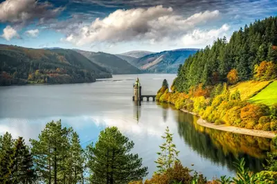 a view of a lake with a tower in the water at Lake Vyrnwy Hotel & Spa in Llanwddyn