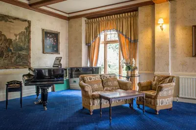 a living room with a piano and two chairs at Lake Vyrnwy Hotel & Spa in Llanwddyn