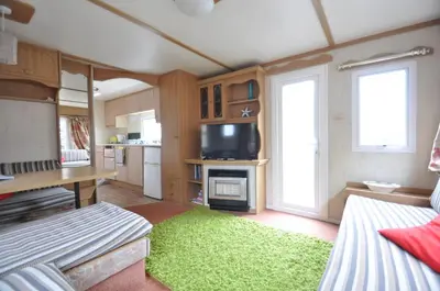 a living room with a television and a green rug at Ideal rural location for beaches, hills and town in Bow Street