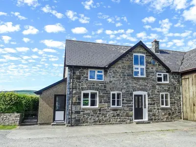 a stone house with a black roof and white windows at Glan Wye in Rhayader