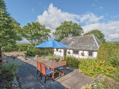 a table with a blue umbrella in front of a house at Pen Copi in Trefeglwys