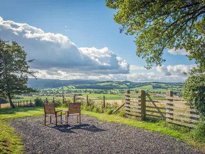 two chairs and a table in front of a fence at Pen Copi in Trefeglwys