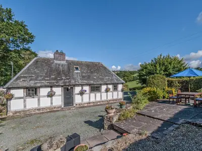 a white cottage with a table and an umbrella at Pen Copi in Trefeglwys