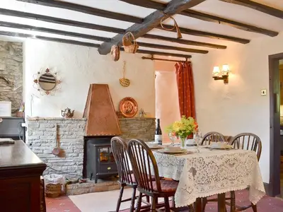 a dining room with a table and a fireplace at Forget Me Not Cottage in New Radnor
