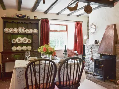 a dining room with a table and a fireplace at Forget Me Not Cottage in New Radnor