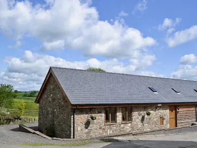 a stone house with a roof on a road at Y Dderwen At Brynglas Farm in Llanfair Caereinion