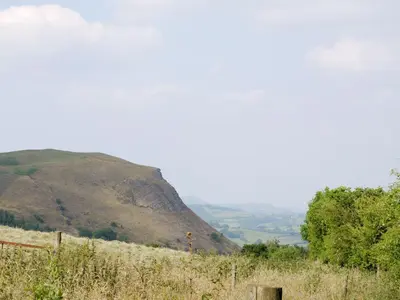 a view of a hill with a fence in the foreground at Hirros Hall Longhouse in Llanerfyl