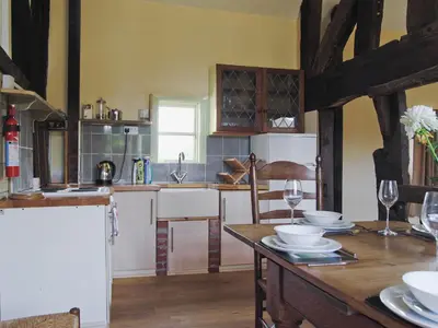 a kitchen with a wooden table with plates and wine glasses at Hirros Hall Longhouse in Llanerfyl