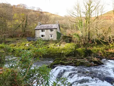 a house on a hill next to a river at Pen y Bont in Machynlleth