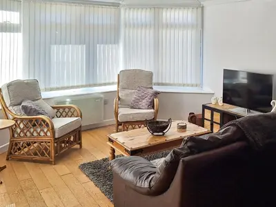 a living room with a couch and chairs and a television at Bwthyn Gwyn in Ciliau-Aeron