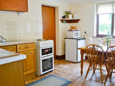 a kitchen with a table and a white oven at Greenmeadow Bungalow in Llanon