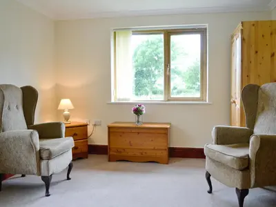 a living room with two chairs and a window at Greenmeadow Bungalow in Llanon