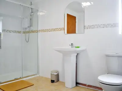 a white bathroom with a sink and a shower at Greenmeadow Bungalow in Llanon