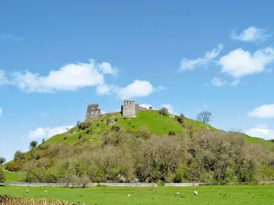 a castle on top of a hill in a field at Greenmeadow Bungalow in Llanon