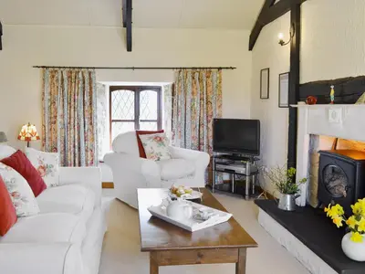 a living room with white furniture and a fireplace at Bwthyn in New Quay