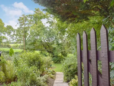 a fence in a garden with a walkway at Bwthyn in New Quay
