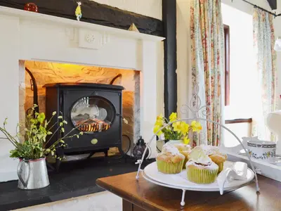 a living room with a fireplace with cupcakes on a table at Bwthyn in New Quay