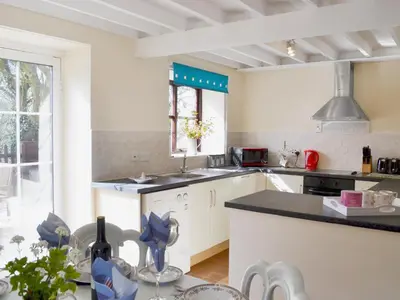 a kitchen with white cabinets and a black counter top at Bwthyn in New Quay