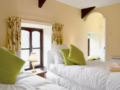 a bedroom with two white beds with green pillows at Bwthyn in New Quay