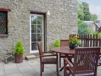 a patio with a table and chairs and a building at Bwthyn in New Quay