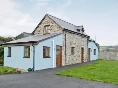 an old stone house with a garage at Bryncrwn Cottage in Rhyd-y-felin