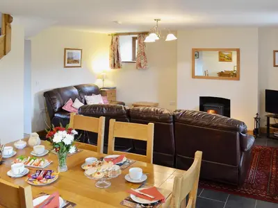 a living room with a table and a leather couch at Llechwedd Mawr in Scyborycoed